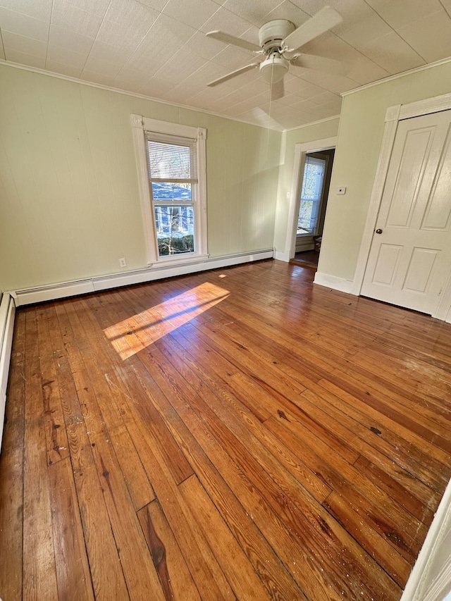 spare room featuring a baseboard heating unit, hardwood / wood-style flooring, plenty of natural light, and ceiling fan