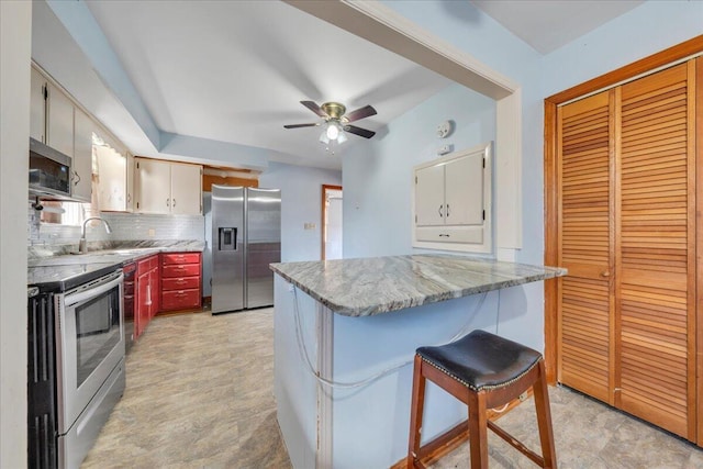 kitchen with tasteful backsplash, sink, ceiling fan, stainless steel appliances, and light stone countertops