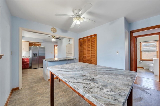 kitchen with stainless steel fridge with ice dispenser, light hardwood / wood-style floors, ceiling fan, and a kitchen island