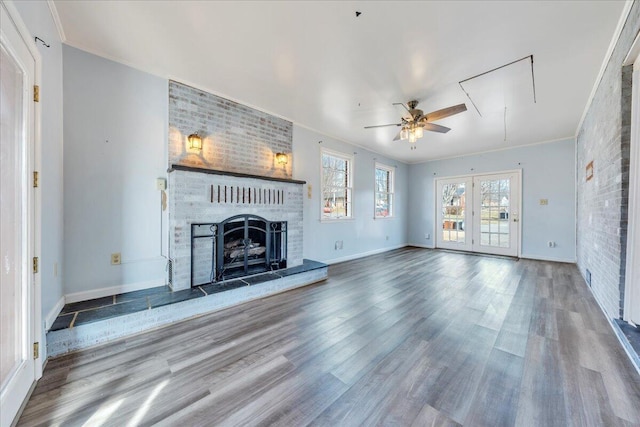 unfurnished living room with crown molding, hardwood / wood-style flooring, ceiling fan, brick wall, and a fireplace