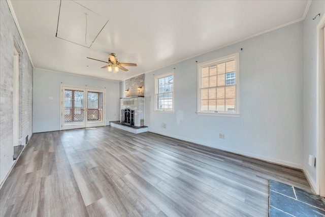 unfurnished living room featuring crown molding, ceiling fan, wood-type flooring, and a fireplace