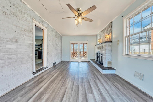 unfurnished living room featuring hardwood / wood-style flooring, ceiling fan, a fireplace, ornamental molding, and brick wall