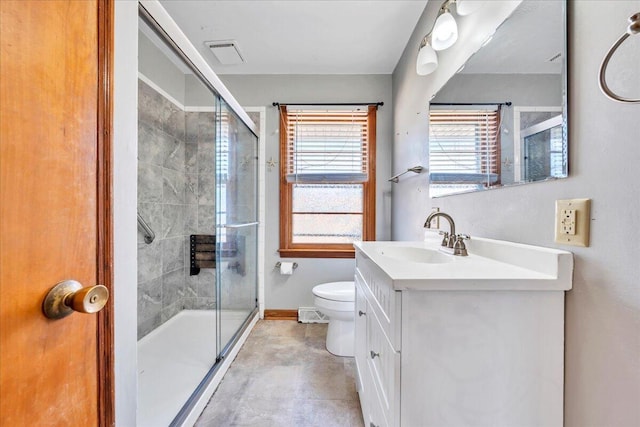 bathroom with toilet, vanity, and a shower with shower door