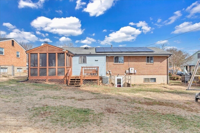 rear view of property with central AC, solar panels, a yard, a deck, and a sunroom