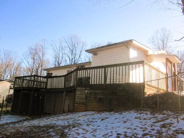 snow covered house featuring a wooden deck