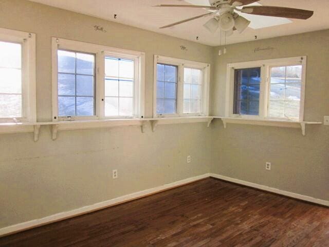 empty room featuring plenty of natural light, dark hardwood / wood-style floors, and ceiling fan