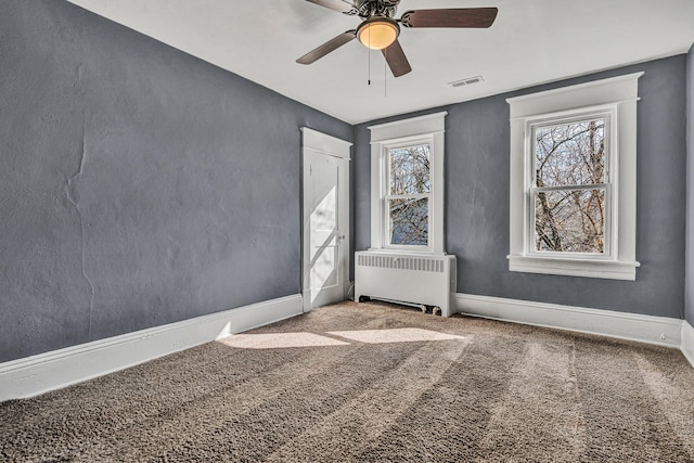 unfurnished room with ceiling fan, radiator, and carpet floors
