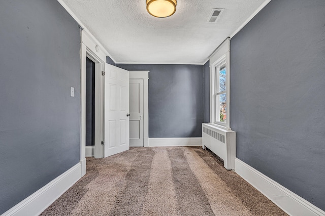 interior space featuring crown molding, carpet, radiator, and a textured ceiling