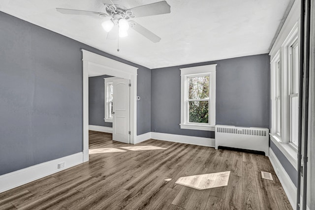 spare room with ceiling fan, wood-type flooring, and radiator