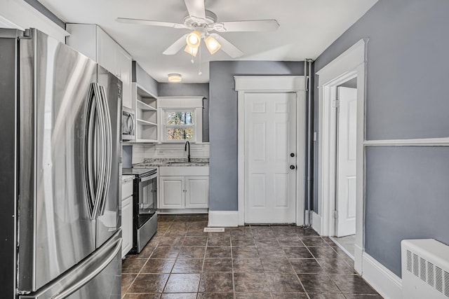 kitchen with stainless steel appliances, white cabinetry, sink, and ceiling fan