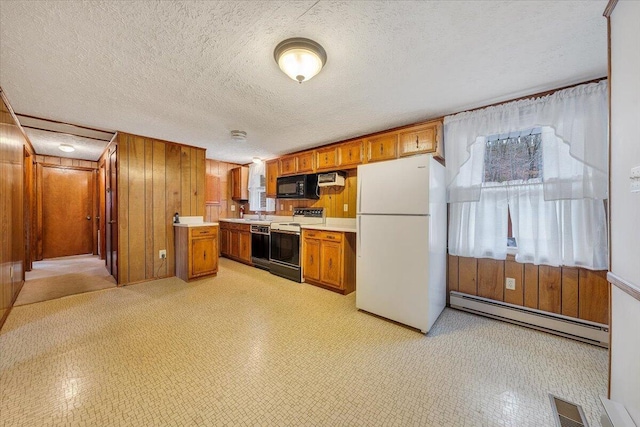 kitchen featuring baseboard heating, wooden walls, a textured ceiling, and black appliances