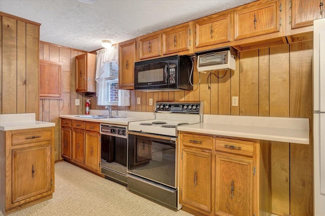 kitchen with wooden walls, sink, a textured ceiling, and black appliances