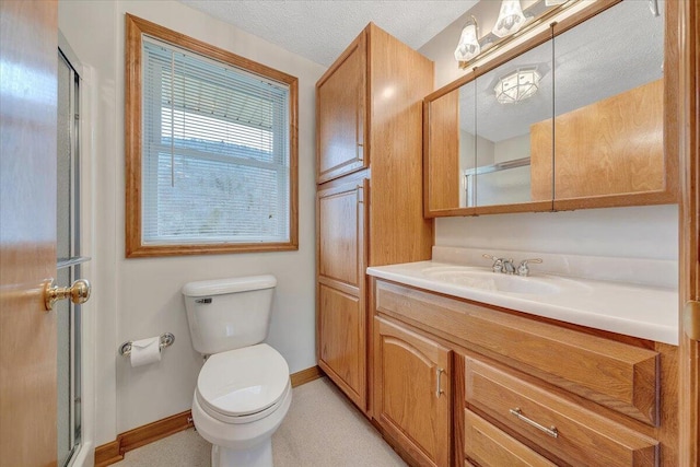 bathroom with vanity, a textured ceiling, a shower with shower door, and toilet