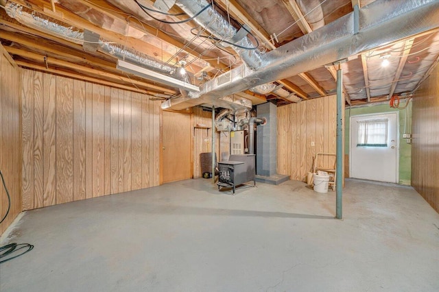 basement with a wood stove, heating unit, and wood walls