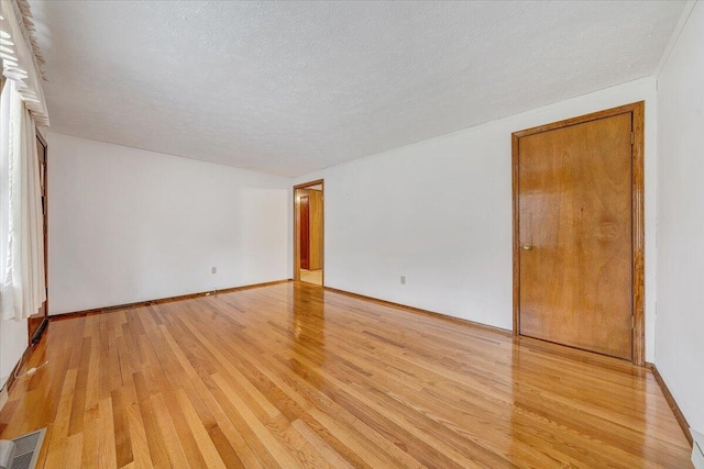 empty room with light hardwood / wood-style flooring and a textured ceiling