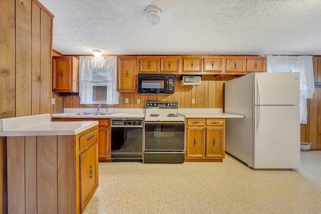 kitchen featuring wooden walls, sink, a textured ceiling, and black appliances