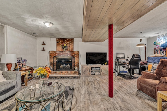 living room with hardwood / wood-style floors, a brick fireplace, and a textured ceiling