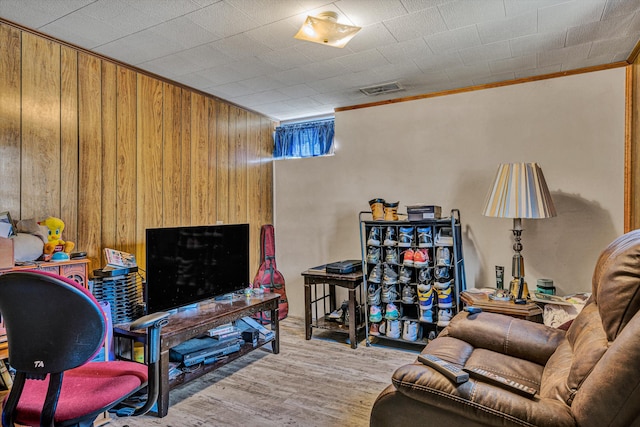 interior space featuring crown molding, wood walls, and light hardwood / wood-style flooring