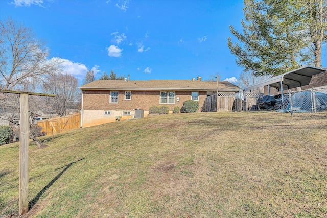 back of property with a carport, central AC unit, and a lawn