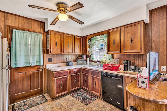 kitchen with sink, ceiling fan, dishwasher, white fridge, and wood walls