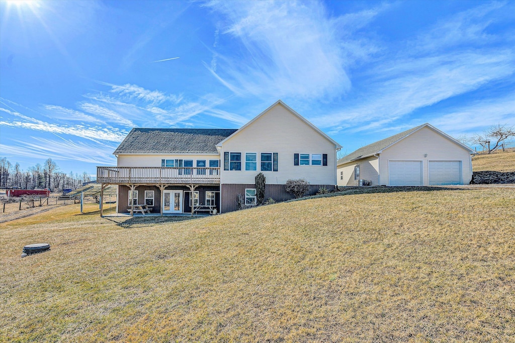 rear view of property featuring a garage, an outdoor structure, a yard, and a deck