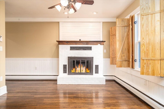 unfurnished living room featuring a baseboard radiator, dark hardwood / wood-style flooring, a wealth of natural light, and a fireplace