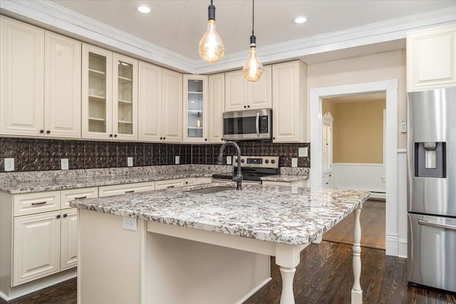 kitchen with appliances with stainless steel finishes, sink, light stone countertops, dark wood-type flooring, and a center island with sink