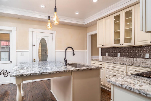 kitchen featuring sink, light stone counters, crown molding, pendant lighting, and cream cabinets