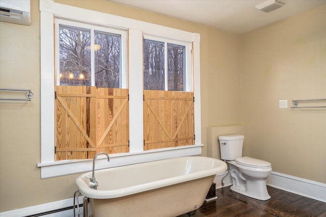 bathroom featuring a tub to relax in, hardwood / wood-style flooring, a baseboard radiator, and toilet