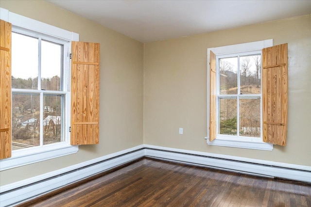 unfurnished room featuring wood-type flooring, a baseboard heating unit, and a wealth of natural light