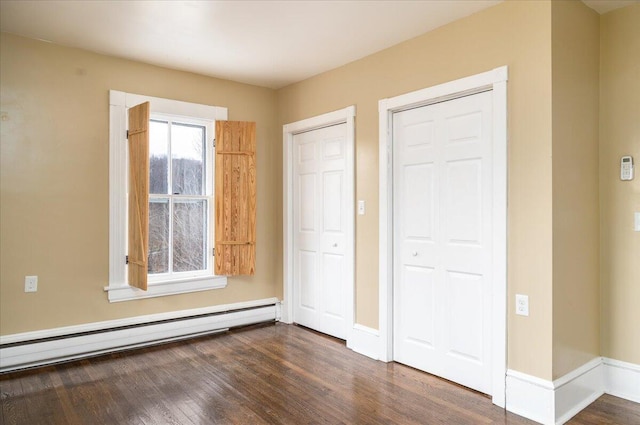 unfurnished bedroom with dark hardwood / wood-style flooring and a baseboard radiator