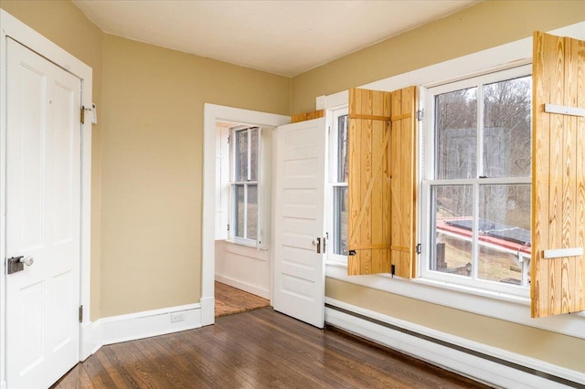 unfurnished bedroom with a baseboard heating unit and dark wood-type flooring