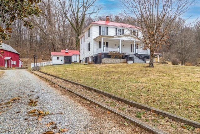 view of front facade featuring an outdoor structure, a front yard, and covered porch