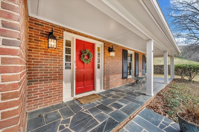 entrance to property with brick siding and a porch