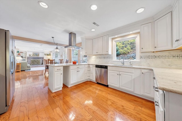 kitchen with a peninsula, a sink, stainless steel appliances, extractor fan, and open floor plan