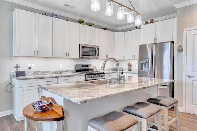 kitchen with sink, an island with sink, white cabinets, and appliances with stainless steel finishes