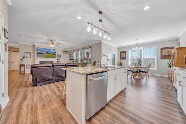 kitchen with white cabinetry, hanging light fixtures, light stone counters, a center island with sink, and stainless steel dishwasher