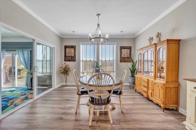 dining space with hardwood / wood-style flooring, crown molding, and a chandelier