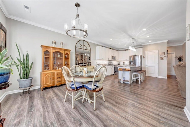 dining area with hardwood / wood-style flooring, ornamental molding, and a chandelier