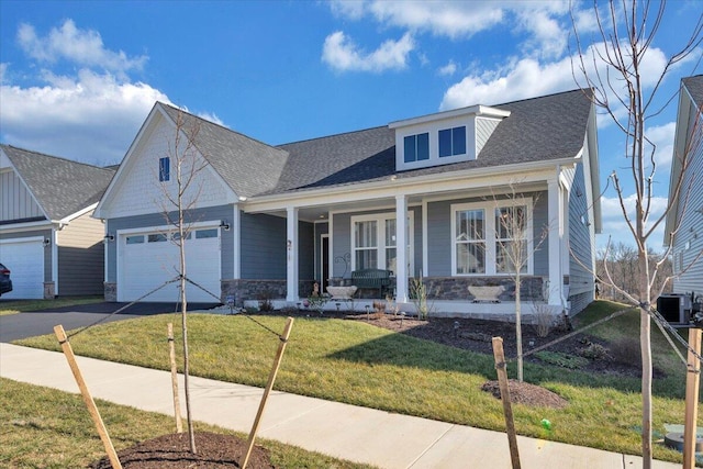 view of front of property featuring a porch, a garage, central AC unit, and a front lawn