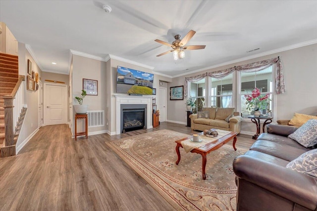 living room featuring wood-type flooring, ornamental molding, and ceiling fan