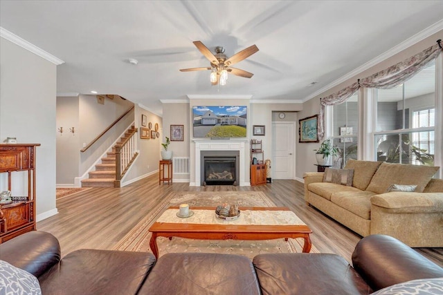 living room with light hardwood / wood-style flooring, ornamental molding, and ceiling fan