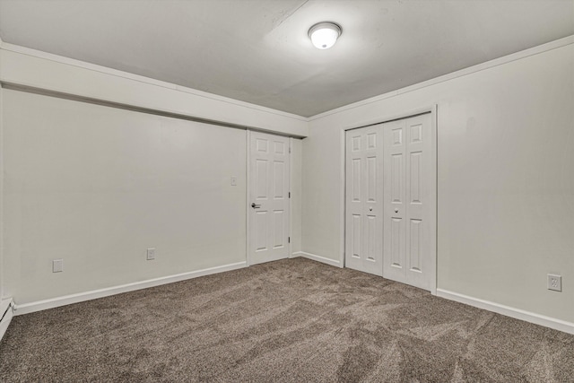 unfurnished bedroom featuring a baseboard heating unit, dark carpet, and a closet