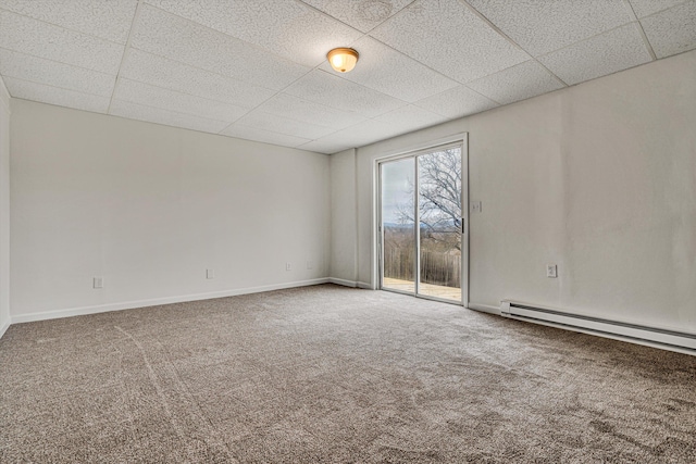 empty room featuring a drop ceiling, a baseboard heating unit, and carpet