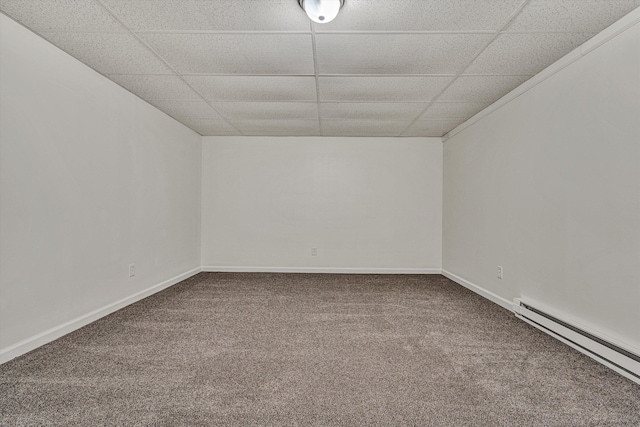 carpeted empty room featuring a baseboard heating unit and a paneled ceiling