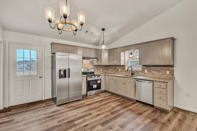 kitchen with vaulted ceiling, appliances with stainless steel finishes, sink, and hanging light fixtures