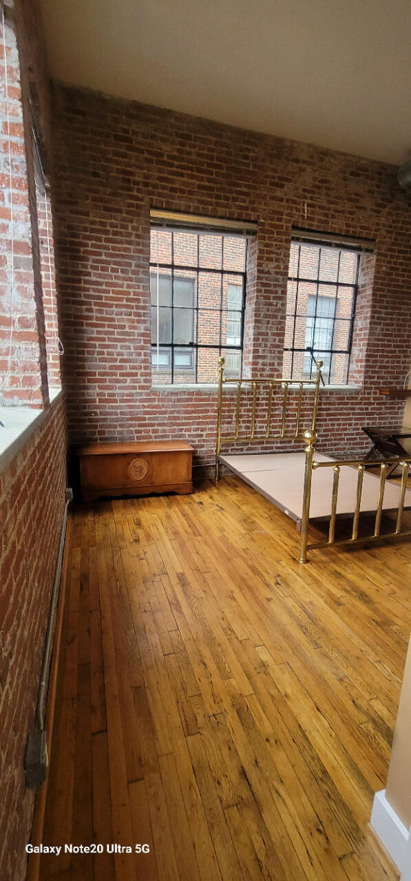 spare room featuring brick wall and wood-type flooring