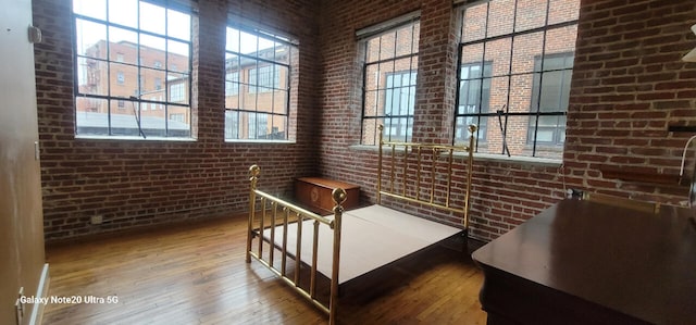 interior space with hardwood / wood-style flooring and brick wall