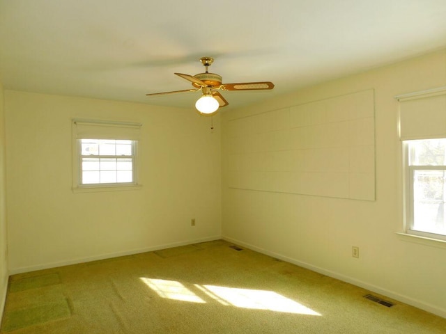 carpeted empty room with ceiling fan and a healthy amount of sunlight