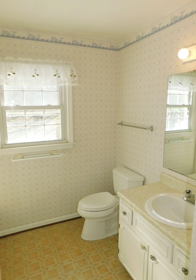 bathroom with plenty of natural light, toilet, and vanity